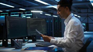 Admin in data center maintaining accurate documentation of infrastructure, configurations and procedures, generating reports. Server room employee doing workspace disaster recovery planning, camera B photo