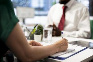 HR employee filling in paperwork after making sure candidate possesses skills needed to fulfil role. HR manager signing contract after evaluating if applicant qualifications align with company values photo