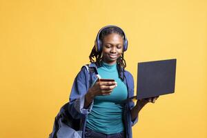 Joyful woman adding payment method on website using laptop, enjoying sales period, isolated over studio background. Girl doing purchases on internet, typing credit card information on notebook photo