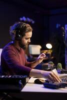 Audio engineer using stereo console to add sound effects on songs, working with daw software on pc for post production. Composer songwriter producing new tracks with amplifier and recordings. photo