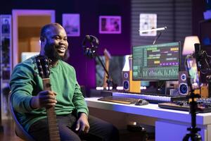 Musical composer hosting online guitar lessons with tutorial on smartphone, recording himself playing acoustic instrument. Young artist teaching people how to play accords on strings, vlog. photo