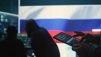 Person uses tablet in governmental cyber security room working under the Russian flag. Making cyber threats, hacking systems to gain unauthorized access, and spreading fake news. Close up. Camera B. photo