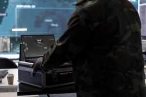 Military specialist monitors satellite data real time information on laptop, coordinates strategic operations to support decision making and national protocols in a high tech control room. photo