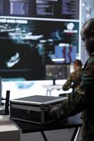Army soldier handles satellite radar real time data on laptop in command post, coordinates strategic missions to support national defense operations in a high tech military base. Close up. photo