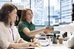 Cheerful businesspeople in office shaking hands after finishing lucrative business transaction. Happy management board doing meeting, doing welcoming handshake gesture before starting conversation photo