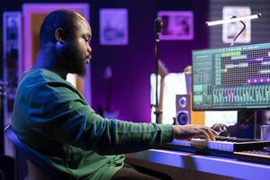 Musician playing piano keyboard and recording tracks for mix and master session, using digital software on pc to create new songs. Sound producer composing music with midi controller tool. photo