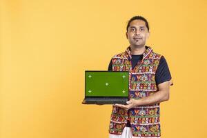 Portrait of smiling man holding green screen laptop, doing important work for company, isolated over studio background. Employee with mockup on notebook device, isolated over studio backdrop photo