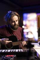 Professional singer teaching guitar lessons online on social media channel, recording himself playing acoustic instrument accords and explaining notes on strings. Young artist making tutorials. photo