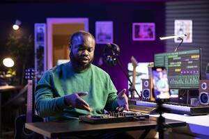 Sound designer presenting all controls on a mixing console during master class lesson on an online vlog, home studio. Artist gives explanations about pre amp knobs and motorized faders. photo