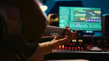 Skilled artist guitarist recording a new song with electro acoustic guitar, composing and editing music in professional studio control room. Young musician songwriter creating tunes. Camera A. photo