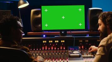 Diverse producers mixing and mastering tracks with mockup display on computer, recording before adding effects in post production. Artist and sound engineer twisting control desk knobs. Camera A. photo