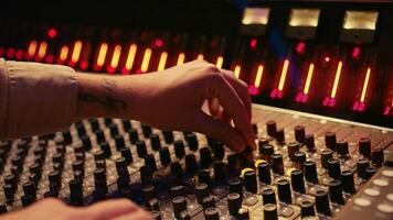 Audio technician twisting pre amp knobs and buttons on panel board in control room, using editing console for mixing and mastering tracks. Professional tracking engineer in music studio. Camera B. photo