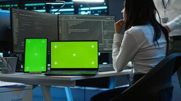 Engineers in data center monitoring security threats using chroma key devices. Experts using isolated screen tablet and laptop, ensuring compliance with regulations, camera A photo