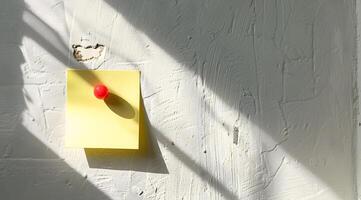 Yellow Sticky Note, Red Pushpin, Textured White Wall photo