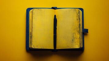 Yellow notebook with pen on yellow background photo