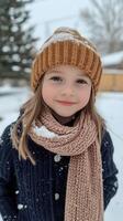 A little girl wearing a hat and scarf in the snow photo