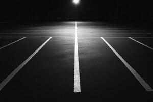 Black and white photograph of empty parking lot at night photo