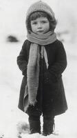 A young girl in a winter coat and hat standing in the snow photo