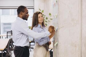 Business colleagues collaborating, using sticky notes on a wall in a modern office environment photo