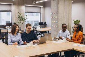 Professional team collaborating, using digital devices, brainstorming project details in contemporary workplace with natural lighting photo