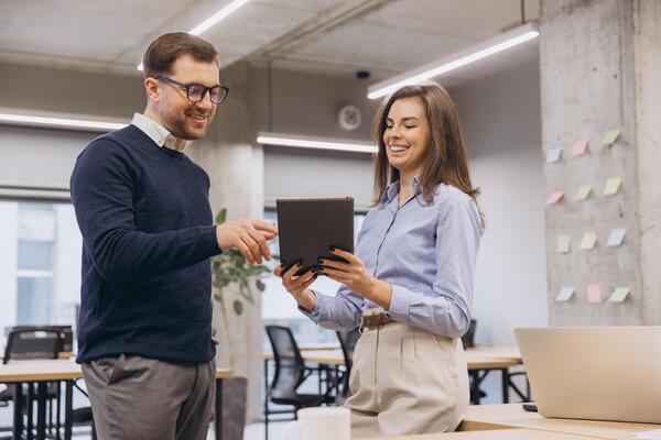 Smiling business colleagues using digital tablet while discussing project in modern office