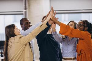 Diverse business team connecting hands, expressing unity and achievement in contemporary workplace environment photo