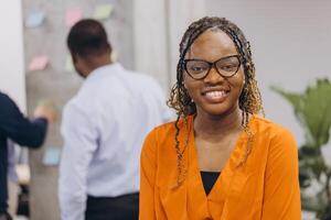 Portrait of smiling african american businesswoman, diverse professionals collaborating, sharing ideas during dynamic team brainstorming meeting in modern office workspace photo