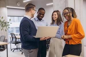 Smiling diverse professionals collaborating, sharing laughter during team project at modern office, embodying workplace camaraderie and inclusivity photo
