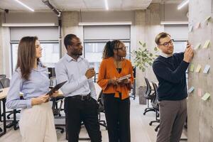 Business team collaborating on a project, using sticky notes on a wall in a modern office photo