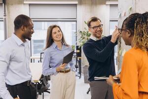Business colleagues discussing work using sticky notes on a wall, showcasing teamwork and collaboration in a modern office environment photo
