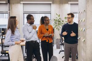 Group of diverse business people discussing new ideas using sticky notes during a productive meeting in a modern office environment photo