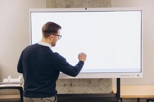 Business professional using an interactive whiteboard to analyze data and graphs in a modern office setting, focusing on strategic planning photo