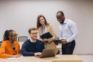 Diverse colleagues collaborating, discussing project details, sharing digital screens and strategies in contemporary workspace photo