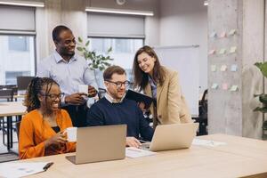 Professional team collaborating over laptops, sharing ideas and working together in modern workspace, showcasing corporate synergy photo