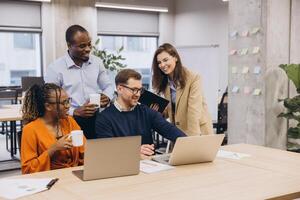 Diverse team collaborating, brainstorming with digital devices in modern workplace, highlighting teamwork and innovative communication photo