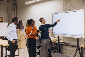 Diverse group of professionals engaging in a collaborative discussion around a digital whiteboard in a modern office setting photo
