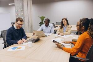 Professionals engaged in a business meeting, discussing charts and data on digital devices in a contemporary office environment photo