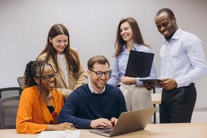 Group of diverse professionals engaged in a collaborative work session, sharing ideas and using technology in a modern office environment photo