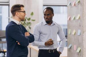 Two business professionals engage in a strategic discussion, surrounded by colorful sticky notes in a contemporary office environment photo