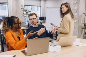Professional team collaborating during high tech meeting, sharing insights using laptops and digital technology in modern workspace photo