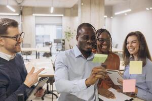 Diverse group of professionals brainstorming with sticky notes in a modern office. Teamwork and creativity in a collaborative workspace photo