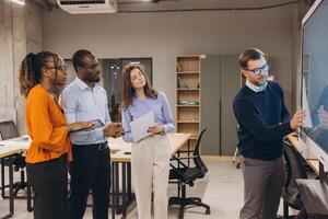 Professional team collaborating, analyzing strategies on digital whiteboard, diverse colleagues connecting in contemporary workspace photo