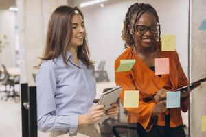Business professionals collaborating, brainstorming project concepts while writing notes on glass board in contemporary workspace photo