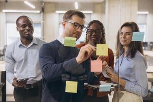 Group of diverse professionals brainstorming and collaborating on a project using sticky notes in a modern office setting photo