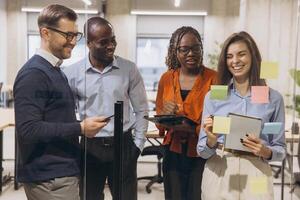 Group of professionals brainstorming in a modern office, using sticky notes and digital devices for innovative project planning and teamwork photo