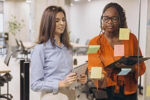 Two professionals brainstorm with sticky notes on a glass wall in a contemporary office, showcasing teamwork and creative problem solving photo