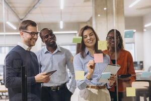 Group of professionals brainstorming in a contemporary office, using sticky notes and tablets for creative business planning and teamwork photo