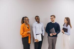 Professional team collaborating, diverse colleagues standing close, sharing laptops and documents, representing corporate unity and strategic communication photo