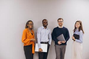 Diverse business team standing together in corporate workspace, working collaboratively with laptops, displaying professional unity and shared goals photo