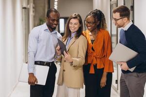 Multicultural business team collaborating, brainstorming with digital devices in contemporary workspace photo